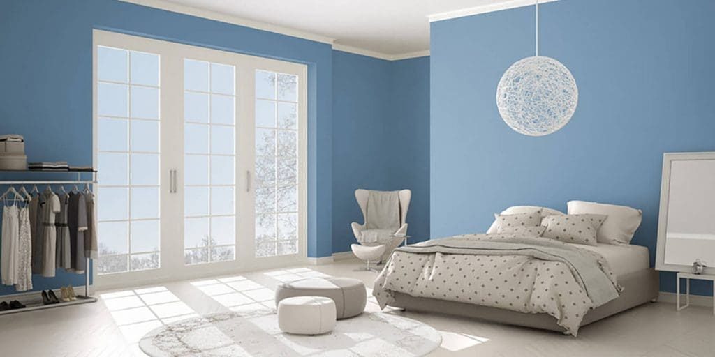 Bright bedroom with soft blue paint walls and white trim showing how paint color affects perceived room size